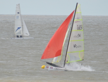 The Spitfire catamaran kicks up a plume of spray as it heads round the buoy