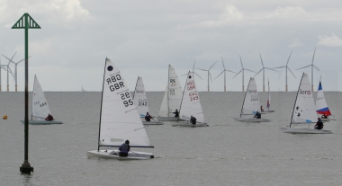 Andy Dunnett crosses the start line first in his Laser, ahead of Clare Giles in her Europe close by the IDM