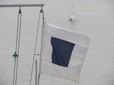 The shorten course flag gently flies as Robert Mitchell sails towards the finish line.....