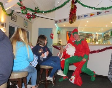 The diminutive elf tests the strength of Father Christmas's leg