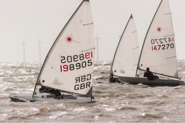 With the mainsheet block to block, and a good bend in the mast, John Tappenden drives his Laser hard on starboard tack, moments after the start.  Ken Potts can be seen behind, on port tack, an error of judgement that cost him the race